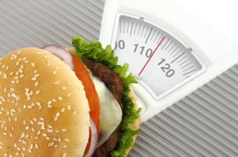 Burger on a weight scale 스톡 사진