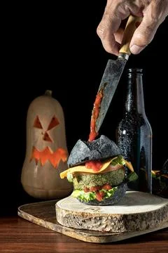 Burgers with black bread, one hand grips a knife Halloween style, day of th.. Stock Photos