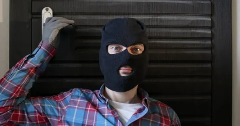 Burglar in black balaclava pulls handle of apartment door 스톡 동영상 314717665