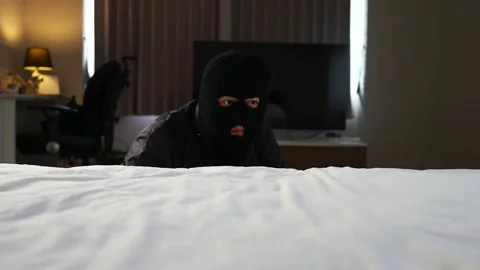 Burglar climbing up on the bed. Stockbeeldmateriaal 203806097