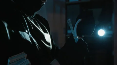 Burglar Examining Stack of Dollar Bills and Nodding during Break-In at Night Stock Footage 321678193