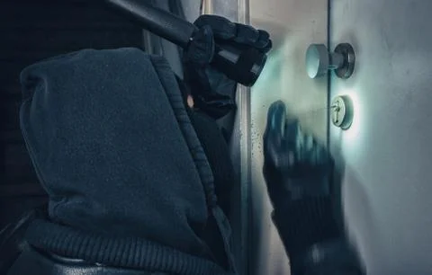 Burglar with lock picking tools breaking into a house door Stock Photos