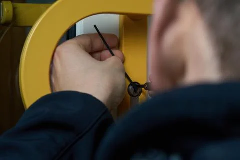 Burglar with lockpick tool opens the front door to enter the house. Also key Stock Photos