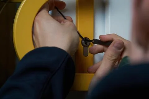 Burglar with lockpick tool opens the front door to enter the house. Also key Stock Photos