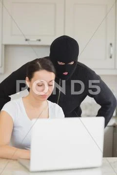 Burglar looking at the laptop behind woman Stock Photos