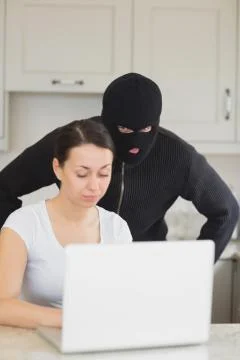Burglar looking at the laptop behind  woman Stock Photos