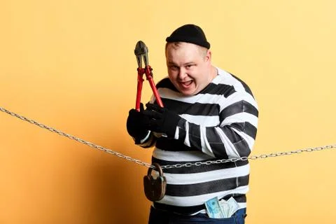 Burglar with scissors in hands looking at the camera while standing behind the Stock Photos