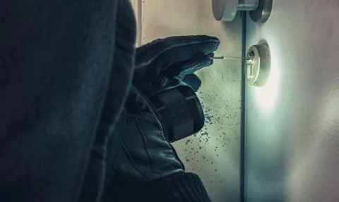 Burglar using picking tools to open a victim's door Foto stock