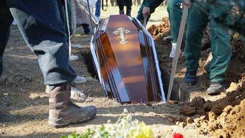 Burial. Men lower the coffin into the grave. Foto stock