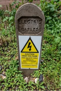 Buried electric cables identification and warning post Stock Photos