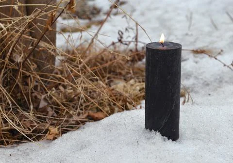 Buring black candle in snow, magic ritual. Esoteric, gothic and occult backgr Photos