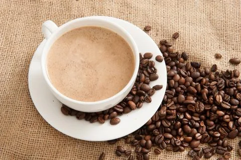 Burlap background with coffee cup and coffee beans top view Stock Photos