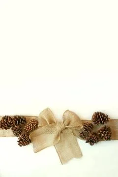 Burlap christmas bow with pinecones isolated on white background Stock Photos
