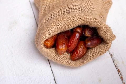Burlap sack of Dried dates on white wooden background. Close-up Stock Photos