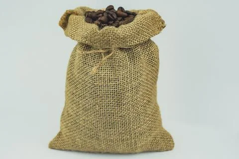 Burlap sack filled with roasted coffee beans on white background Stock Photos