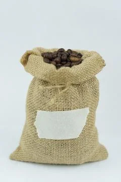 Burlap sack of roasted coffee beans with blank label on white background Stock Photos