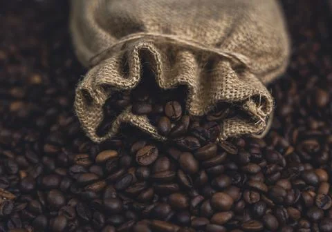 Burlap sack with roasted coffee beans spilling out Stock Photos