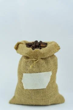 Burlap sack of roasted coffee beans with blank label on white background Stock Photos