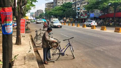 Burmese man loading an old gas cylinder on the back of his bicycle Stockfoto's