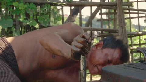 Burmese worker cranking an engine at an unregulated oil field in Myanmar 스톡 동영상 332758059