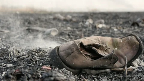 Burned boot in ash on the big burnt field after a fire . War sign. 4k footage Vidéo 105014598
