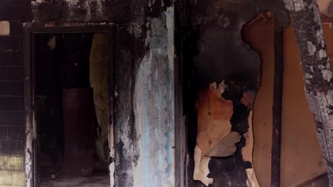 Burned building interior showing charred walls and peeling wallpaper after fire Stock Footage 342025979