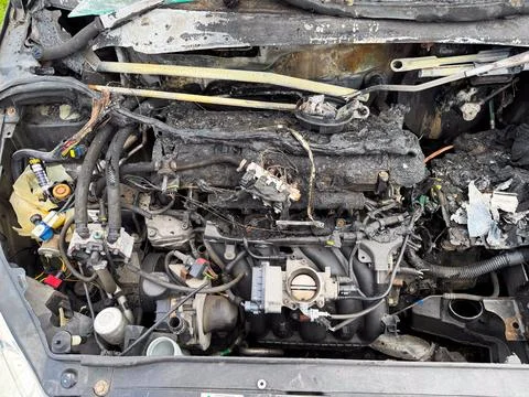 Burned car engine compartment showing fire-damaged engine block, melted wir.. Stock Photos