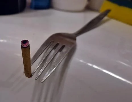 Burned cigarette balanced on a dinner fork Photos
