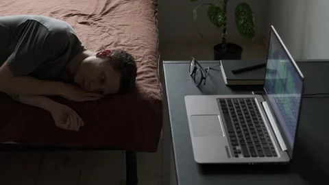 Burned Out Freelancer Lying on Bed Unable to Work, Laptop and Glasses on Desk Stock Footage 309206638