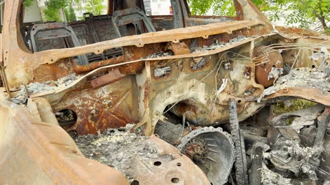 Burned rusted car chassis exposes severe devastation outdoors Stockbeeldmateriaal 336864382