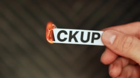 Burning “backup” label held by hand, symbolizing data loss risk, no redundancy Stock Footage 333654240