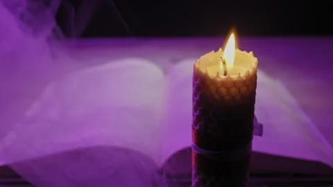 Burning Beeswax Candle and Open Book in Mysterious Purple Smoke Stock Footage 329844169