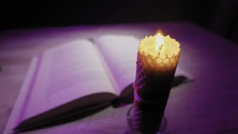 Burning Beeswax Candle with Open Book in Mystical Purple Light Stock Footage 329968250