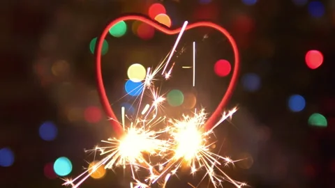 Burning bengal fire in heart shape and sparks on defocused background in 4K Stock Footage 146665464