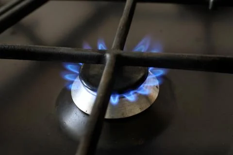 Burning blue gas flame on kitchen stove close up, lit burner ring under bla.. Stock Photos