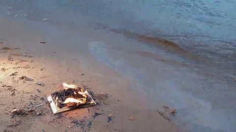 Burning book on the sand at coast Stock Footage 69158946