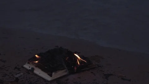Burning book on the sand at coast Stock Footage 74378586