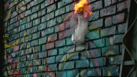 Burning bottle explodes against a hard wall, disintegrating in slow motion. Stock Footage 251623191