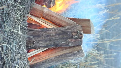 Burning a campfire in the form of a hut made of chopped wood blocks with a Stock Footage 145922283
