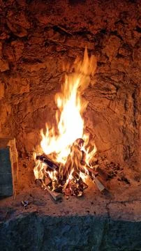 Burning campfire inside a traditional stone fireplace Stock Photos