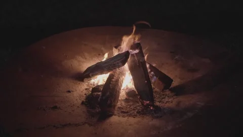 Burning campfire logs glowing under night sky in outdoor fire pit Stockbeeldmateriaal 312194875