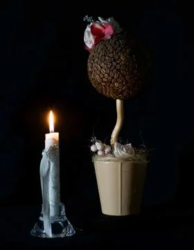 Burning candle, artificial coffee bean flower in the dark on the eve of Easte Stock Photos
