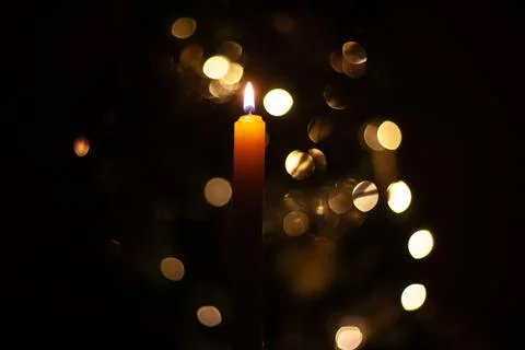 A burning candle on a background of lights Stock Photos