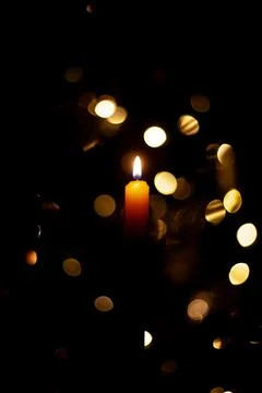 A burning candle on a background of lights Stock Photos