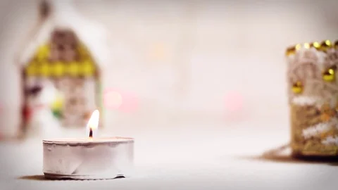 Burning candle on the background of a New Year's toy winter house in light Video stock 82407258