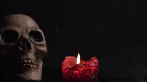 Burning candle on a black background and a blurry image of a skull Stock Footage 155829359