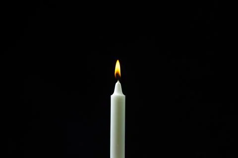 Burning candle on a black background. Fire candles on a dark background. Stock Photos