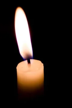 Burning candle on a black background Stock Photos