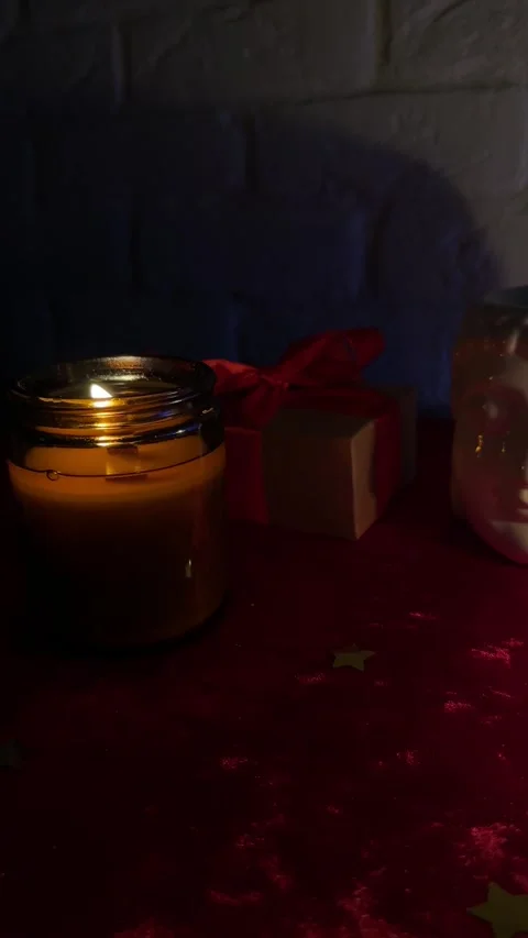 Burning candle with Buddha statue and holiday gift box with red ribbon in cozy d Stock Footage 320676930