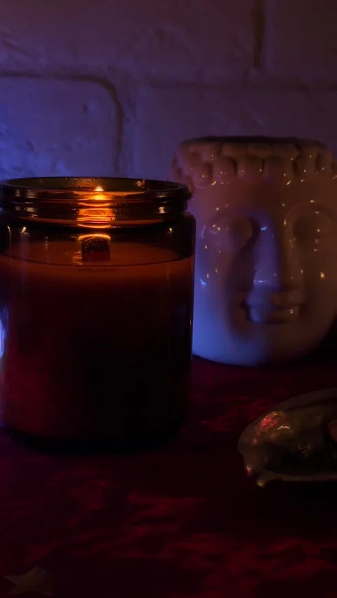 Burning candle with Buddha statue and holiday gift box with red ribbon in cozy d Stock Footage 320676995